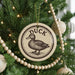 A Christmas tree decorated with ornaments, including a circular ornament with a duck design and a string of wooden beads.