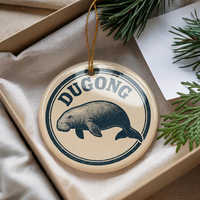 A round ornament with a manatee image and the word "DUGONG" printed on it, hanging from a string.