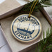 A circular ornament with the text "DUSSELLDORF GERMANY" printed on it, surrounded by a decorative border and a pine branch.