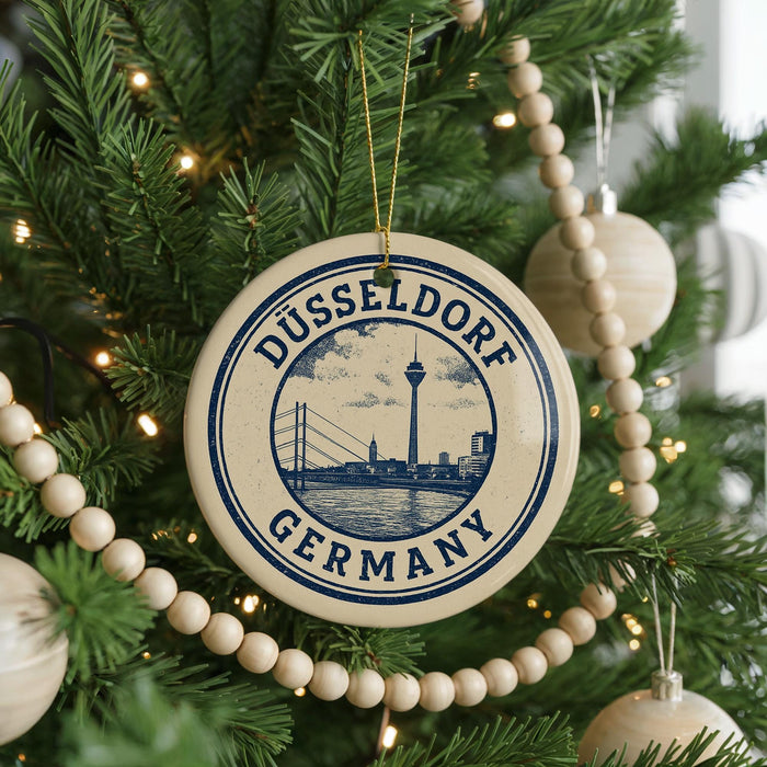 A circular ornament on a Christmas tree, featuring the text "DÜSSELLDORF GERMANY" and an illustration of the Düsseldorf Tower.