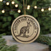 A circular ornament featuring a kangaroo, with the text "EASTERN GRAY KANGAROO" printed on it, is displayed in front of a blurred Christmas tree.