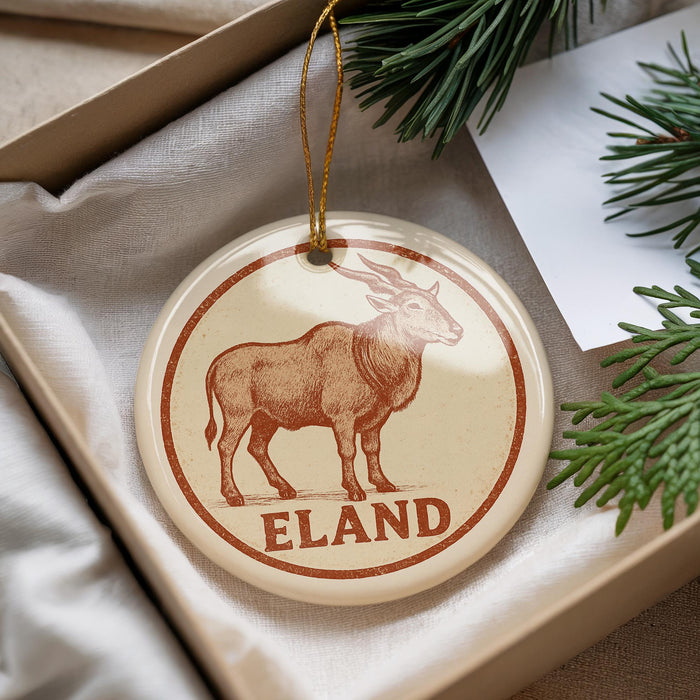 A round ornament with a brown animal, possibly a deer or elk, and the word "ELAND" printed on it, hanging from a string.