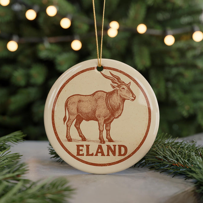A round ornament featuring a brown antelope, with the word "ELAND" written below it, is hanging from a string.