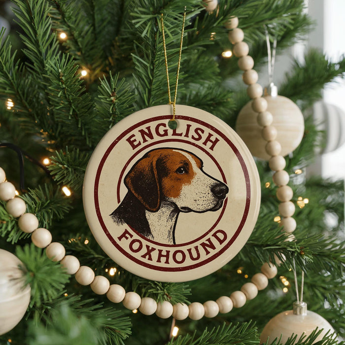 A round ornament on a Christmas tree featuring a foxhound dog's head, with the text "ENGLISH FOXHOUND" around the edge.