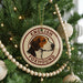 A round ornament on a Christmas tree featuring a foxhound dog's head, with the text "ENGLISH FOXHOUND" around the edge.