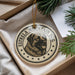 A decorative ornament featuring a dog's head in a circular design with the text "ESTRELLA MOUNTAIN DOG" around it.