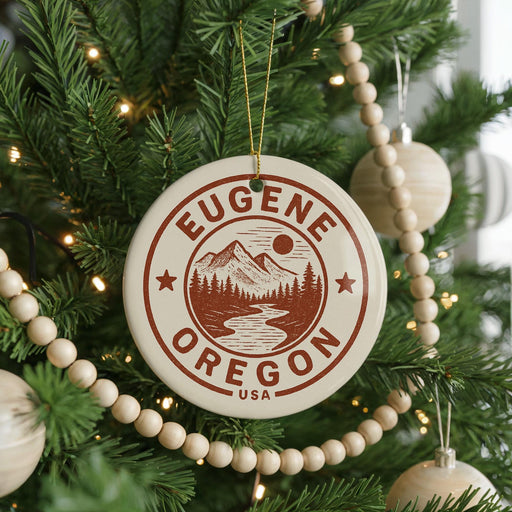 A Christmas tree decorated with ornaments, including a circular ornament with the text "EUGENE OREGON USA" and a mountain landscape design.