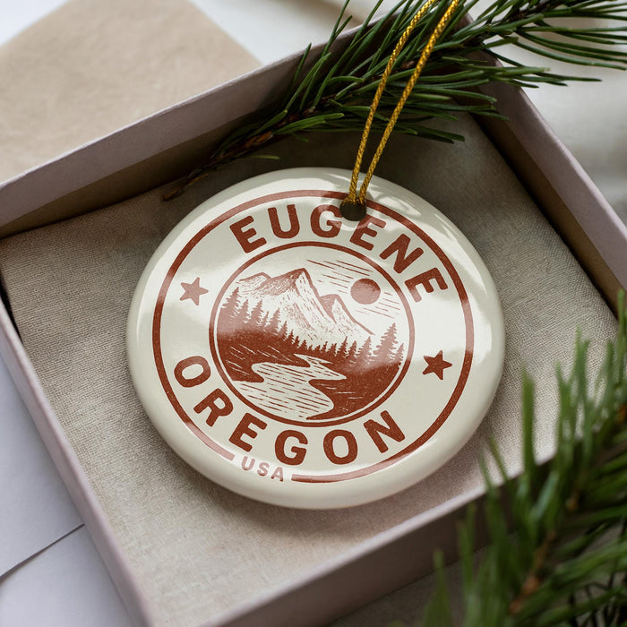 A circular ornament with the text "EUGENE OREGON USA" printed on it, surrounded by pine branches.