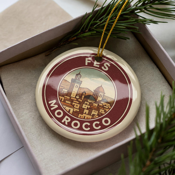 A decorative ornament in a box, featuring a circular design with a cityscape and the text "FES MOROCCO" on it.