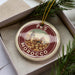 A decorative ornament in a box, featuring a circular design with a cityscape and the text "FES MOROCCO" on it.