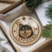 A circular ornament featuring a dog's face with the text "FINISH LAPPHUND" around it, placed on a surface with pine branches and a white paper.