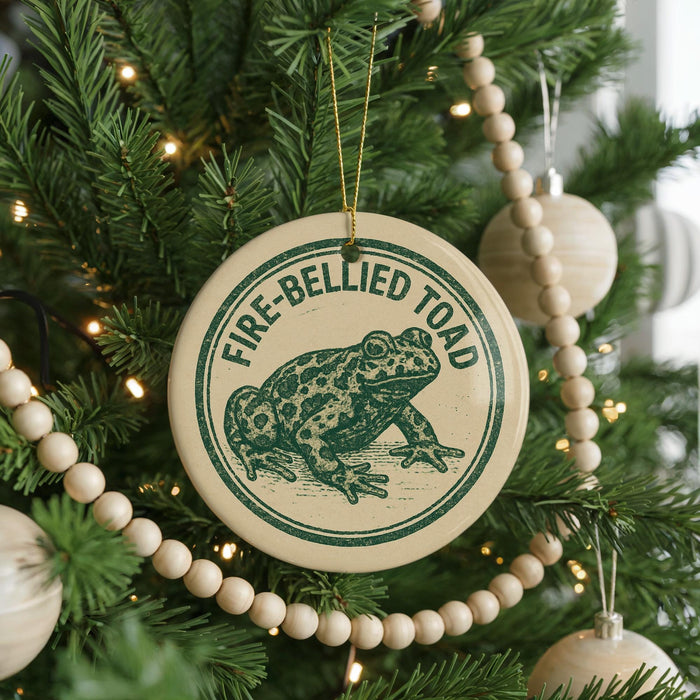 A Christmas tree decorated with ornaments, including a circular ornament with a frog image and the text "FIRE-BELLIED TOAD".