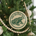 A Christmas tree decorated with ornaments, including a circular ornament with a frog image and the text "FIRE-BELLIED TOAD".