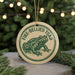A circular ornament featuring a green frog with the text "FIRE-BELLIED TOAD" on it, hanging from a string.