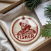 A round ornament with a portrait of a man wearing a hat and the word "FISHER" printed on it, hanging from a string.