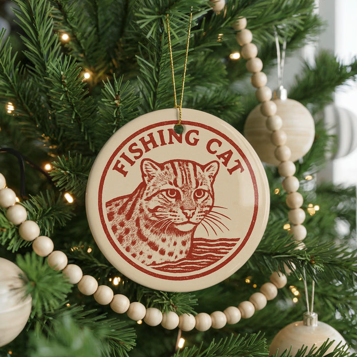 A Christmas tree decorated with ornaments, including a circular ornament with a cat image and the text "FISHING CAT" on it.