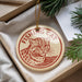 A round ornament with a cat image and the text "Fishing Cat" is displayed in a box, surrounded by pine branches.