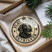 A round ornament with a black and white illustration of a retriever dog, surrounded by text that reads "FLAT-COATED RETRIEVER".
