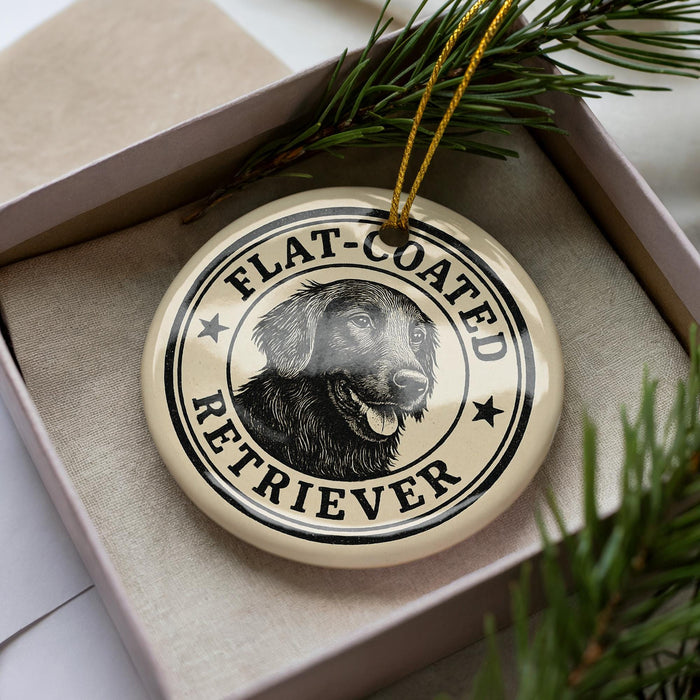 A round ornament with a black and white illustration of a dog's face, surrounded by text that reads "FLAT-COATED RETRIEVER".