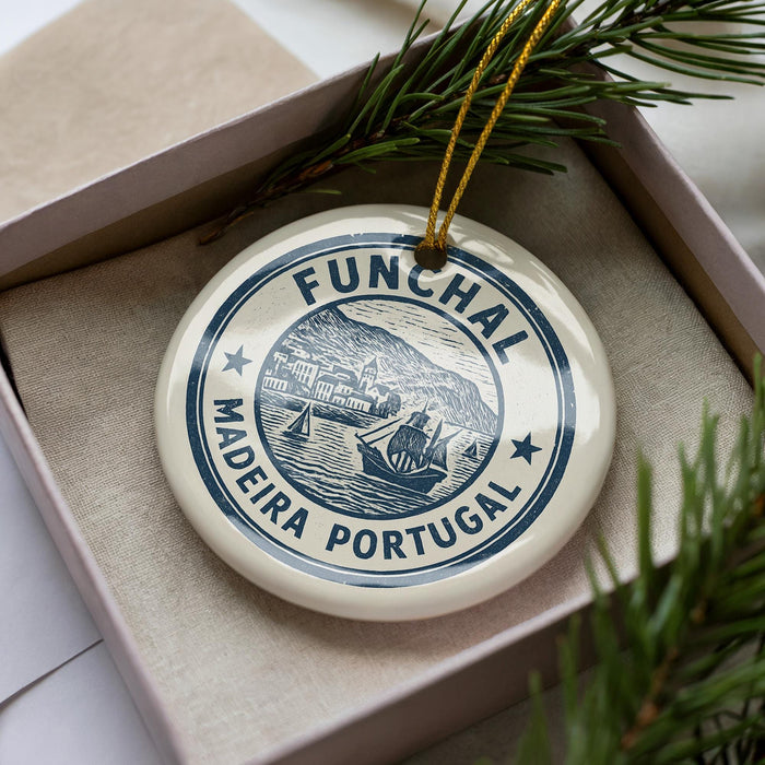 A circular ornament with the text "FUNCHAL MADEIRA PORTUGAL" printed on it, surrounded by pine branches.
