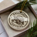 A ceramic ornament in a box, featuring a detailed illustration of a tortoise.
