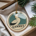 A circular ornament with a bird image and the word "GANNET" printed on it, hanging from a string.