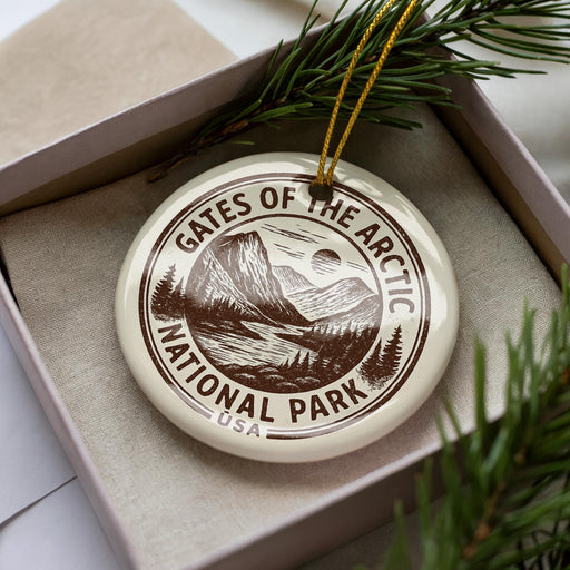 A circular ornament with the text "GATES OF THE ARCTIC NATIONAL PARK USA" printed on it, surrounded by pine branches.