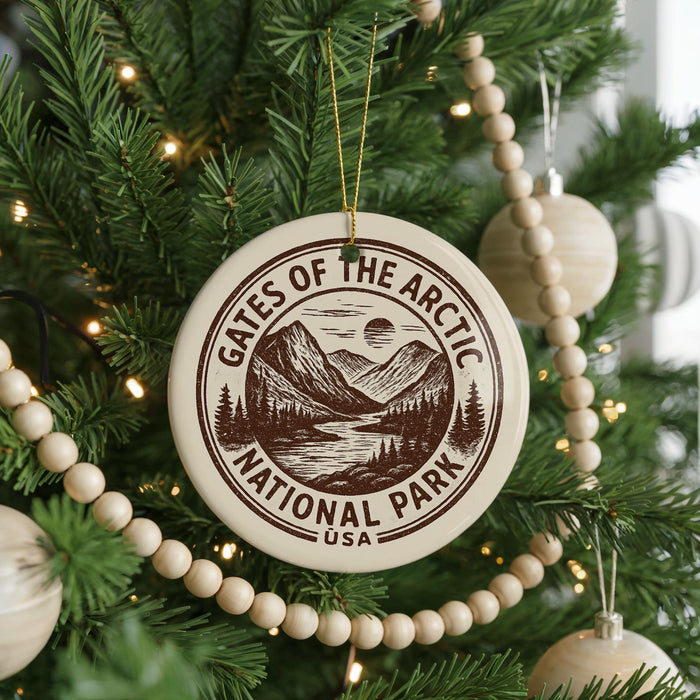 A Christmas tree decorated with ornaments, including a circular ornament with the text "Gates of the Arctic National Park USA" and a wooden bead decoration.