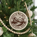 A Christmas tree decorated with ornaments, including a circular ornament with the text "Gates of the Arctic National Park USA" and a wooden bead decoration.