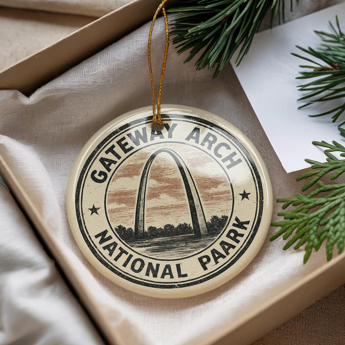 A circular ornament with the words " Gateway Arch National Park" printed on it, hanging from a string.
