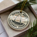 A circular ornament with the words "GATEWAY ARCH NATIONAL PARK" printed on it, surrounded by pine branches.