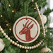 A Christmas tree decorated with ornaments, including a red and white ornament featuring a deer head.