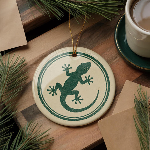 a ceramic ornament with a green lizard design, placed on a wooden surface alongside a cup of coffee and some pine branches.