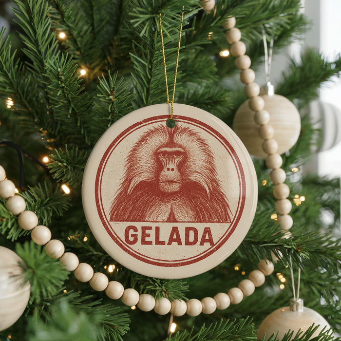 A Christmas tree decorated with ornaments, including a circular ornament with a monkey's face and the word "GELADA" written on it.
