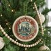 A circular ornament on a Christmas tree, featuring a picture of a city skyline and the text "GHENT BELGIA".