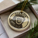 A ceramic ornament in a box, featuring a monkey's face.