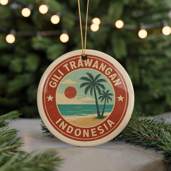 A circular ornament with a palm tree and beach scene, surrounded by a red border, hangs in front of a Christmas tree with twinkling lights.