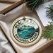 A circular ornament with the text "GLACIER BAY NATIONAL PARK" and a mountain landscape design, hanging from a string.