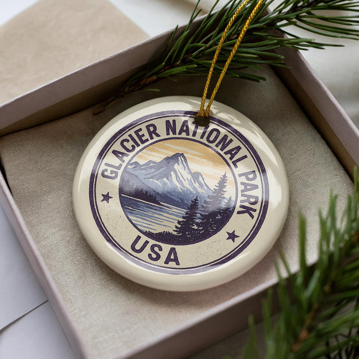 A circular ornament with the text "GLACIER NATIONAL PARK USA" printed on it, surrounded by pine branches.