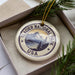 A circular ornament with the text "GLACIER NATIONAL PARK USA" printed on it, surrounded by pine branches.
