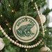 A Christmas tree decorated with ornaments, including a circular ornament with a frog image and the text "GOLIATH FROG" on it.