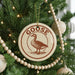 A Christmas tree decorated with ornaments, including a circular ornament with a goose design and the word "GOOSE" written on it.