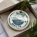 A circular ornament with the text "GOZO MALTA" printed on it, hanging from a string.