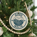 A Christmas tree decorated with ornaments, including a circular ornament with the text "GOZO MALTA" and a small wooden bead decoration.
