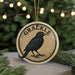 A round ornament with a black bird on it, hanging from a string.