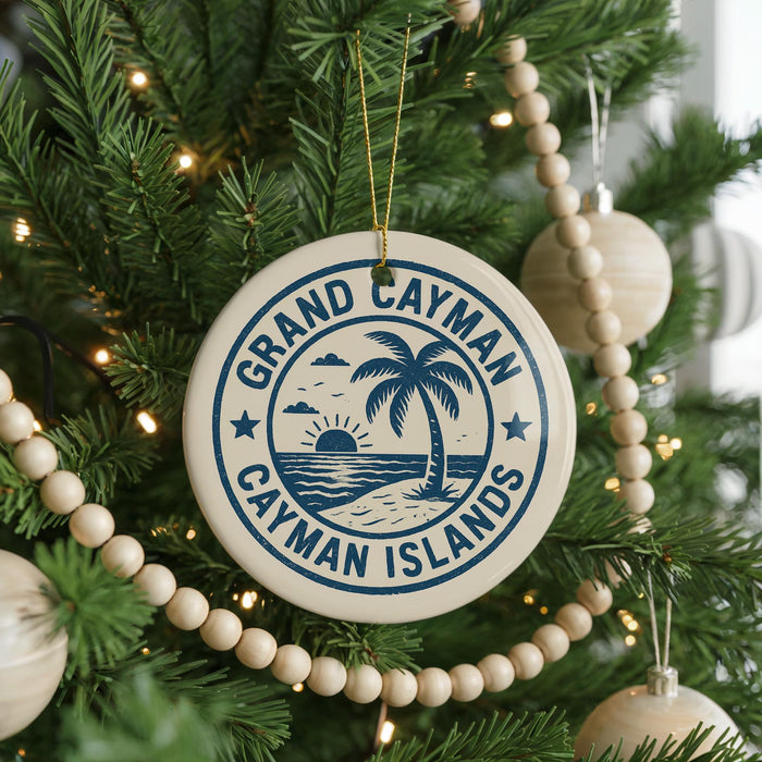 A circular ornament on a Christmas tree, featuring the text "GRAND CAYMAN ISLANDS" surrounded by a palm tree and a beach scene.