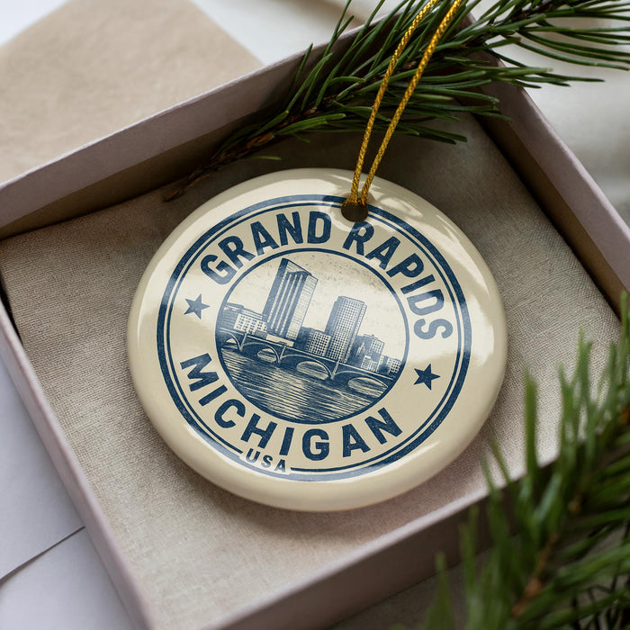 A decorative ornament in a box, featuring a circular design with the text "GRAND RAPIDS MICHIGAN USA" and an illustration of a city skyline.