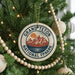 A Christmas tree decorated with ornaments, including a circular ornament with the text "GRAND Teton NATIONAL FPAARK" and a mountain landscape design.