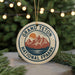 A circular ornament with the text "GRAND Teton NATIONAL FPAARK" and a mountain landscape design, hanging from a string.