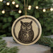 A circular ornament featuring an illustration of an owl is displayed in front of a blurred background of Christmas lights.